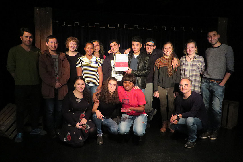 Mitglieder des Figuren Theater Phoenix und des Ensemble LebensWelten stehen auf der Theaterbühne des Figuren Theater Phoenix und halten die Urkunde und die Trophäe des Deutschen Bürgerpreises in Händen.